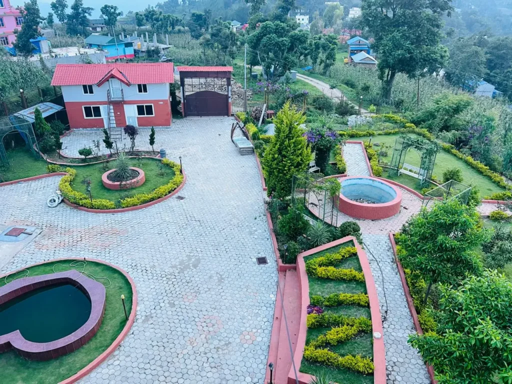 Beautifully landscaped garden with a red-roofed house, pathways, small ponds, and greenery in a peaceful rural setting in Okhaldhunga, Nepal.