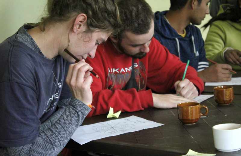 Volunteers in Nepal participate in an orientation workshop, thoughtfully completing a written activity during a community project training session.